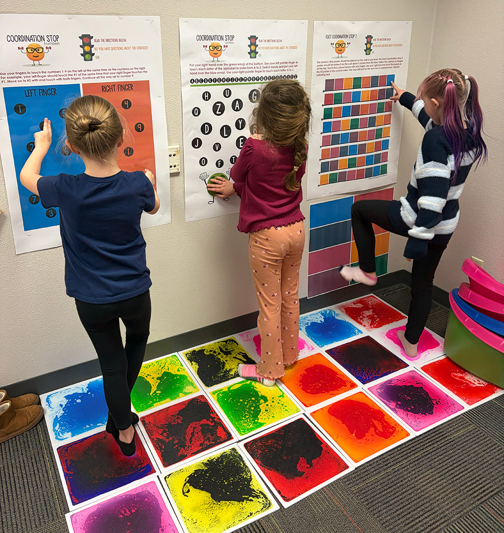 School Block Grant funding helped purchase sensory materials that support students' social-emotional learning. These sensory pads help regulate their emotions using tools funded by ASF. Three students stand on sensory pads and regulate their emotions using tools funded by ASF.